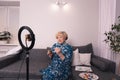 A female blogger artist shows how to use paints to her subscribers sitting at home on the couch in front of a smartphone