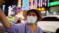 A female blogger is taking a selfie at china town. Influencers wearing masks are narrating and live.