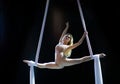 Blond aerial performer with white aerial silks isolated on black background