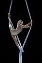 Blond aerial performer with white aerial silks isolated on black background