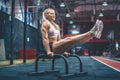 Female blonde athlete performing an exercise in L Sit position on parallel bars at gym. Calisthenic workout. Royalty Free Stock Photo