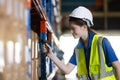 Female blonde hair factory company employee reader scanning code checking number of products on goods shelves in warehouse. Female