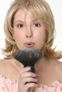 Female blowing excess powder from makeup brush