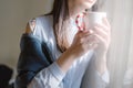 Female in blue shirt by the window with coffe cup Royalty Free Stock Photo