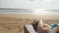 Female body on chaise-longue relaxing and enjoying during summer vacation on empty sandy ocean beach. Young woman lying