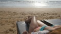 Female body on chaise-longue relaxing and enjoying during summer vacation on empty sandy ocean beach. Young woman lying