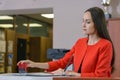 A female Boss in a bright red business suit puts a seal to the contract at the reception office.