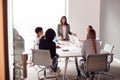 Female Boss Gives Presentation To Team Of Young Businesswomen Meeting Around Table In Modern Office Royalty Free Stock Photo