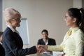 Female boss handshaking Asian employee congratulating with promo