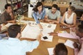 Female Boss Leading Meeting Of Architects Sitting At Table