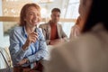 Female boss listening colleague, smiling, laughing, holding glasses