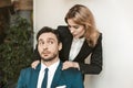 Female boss seduces employee. Young girl holds by the shoulders of a colleague who is sitting at the table. He looks at Royalty Free Stock Photo