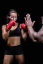 Female boxer with fighting stance against trainer hand Royalty Free Stock Photo