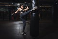 Female boxer hitting a huge punching bag at a boxing studio. Woman boxer training hard. Thai boxer punch kick by punching bag