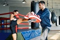 Female boxer kick boxing mitts held by personal trainer at fitness gym