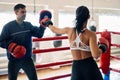 Female boxer kick boxing mitts held by personal trainer at fitness gym
