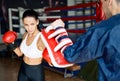Female boxer kick boxing mitts held by personal trainer at fitness gym