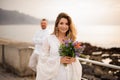 Female bride in white dress standing on the seaside with her groom Royalty Free Stock Photo