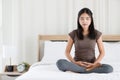 Female Buddhist sitting on bed in the bedroom and doing meditation in Buddhism religion style. The idea for faith and trust in