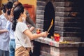 Female Buddhist worshiper burning incense near a Buddhist temple in Vietnam