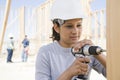 A female builder drilling