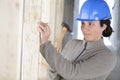 Female builder hammering nail in wooden wall