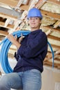 Female builder holding reel blue polyethylene pipe