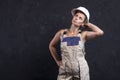 Female builder is posing for camera in studio. Portrait of beautiful woman worker builder in uniform with white helmet