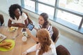 Female business colleagues discussing over digital tablet around breakfast table Royalty Free Stock Photo