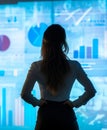A female business leader stands in front of large data charts, analyzing key metrics and projections