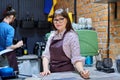 Female business owner in apron standing behind bar counter in coffee shop cafeteria Royalty Free Stock Photo