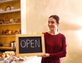 Female business owner holding OPEN sign in bakery Royalty Free Stock Photo