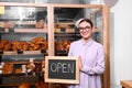 Female business owner holding OPEN sign in bakery Royalty Free Stock Photo