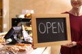Female business owner holding OPEN sign in bakery Royalty Free Stock Photo