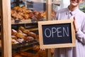 Female business owner holding OPEN sign in bakery Royalty Free Stock Photo