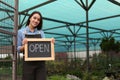 Female business owner holding OPEN sign in greenhouse. Space for text Royalty Free Stock Photo