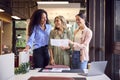 Female Business Team Stand At Desk In Open Plan Office Approving Checking Proofs Or Design Layouts Royalty Free Stock Photo