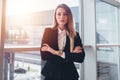 Female business traveler standing against window with airport arrival corridor view