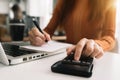 Female businessman hand using calculator and writing make note with calculate about cost.