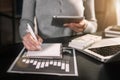 Female businessman hand working at a computer and writing on a notepad with a pen in the office. Royalty Free Stock Photo