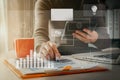 Female businessman hand working at a tablet computer and writing on a notepad with a pen in the office on the wooden desk there a Royalty Free Stock Photo