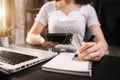 Female businessman hand working at a tablet and writing on a notepad with a pen in the office. Royalty Free Stock Photo