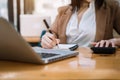 Female businessman working on desk office with using a calculator to calculate the numbers, finance accounting concept Royalty Free Stock Photo