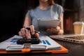 Female businessman working with holding a pen and using a calculator to calculate the numbers of static at home office. Royalty Free Stock Photo