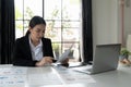 Asian female businesswoman readind financial report analyzing statistics pointing at pie chart working at her desk Royalty Free Stock Photo