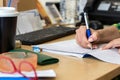 Female bussineswoman hand writing on a paper - notebook on a desk at her office