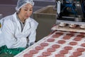 Female butcher processing hamburger patty