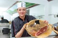 female butcher showing cured ham in basket