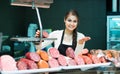 Female butcher with wurst and bologna in meat store counter