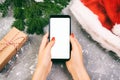 Female buyer makes order at screen of smartphone with copy space. Christmas online shopping. Woman buys presents for xmas. Winter Royalty Free Stock Photo